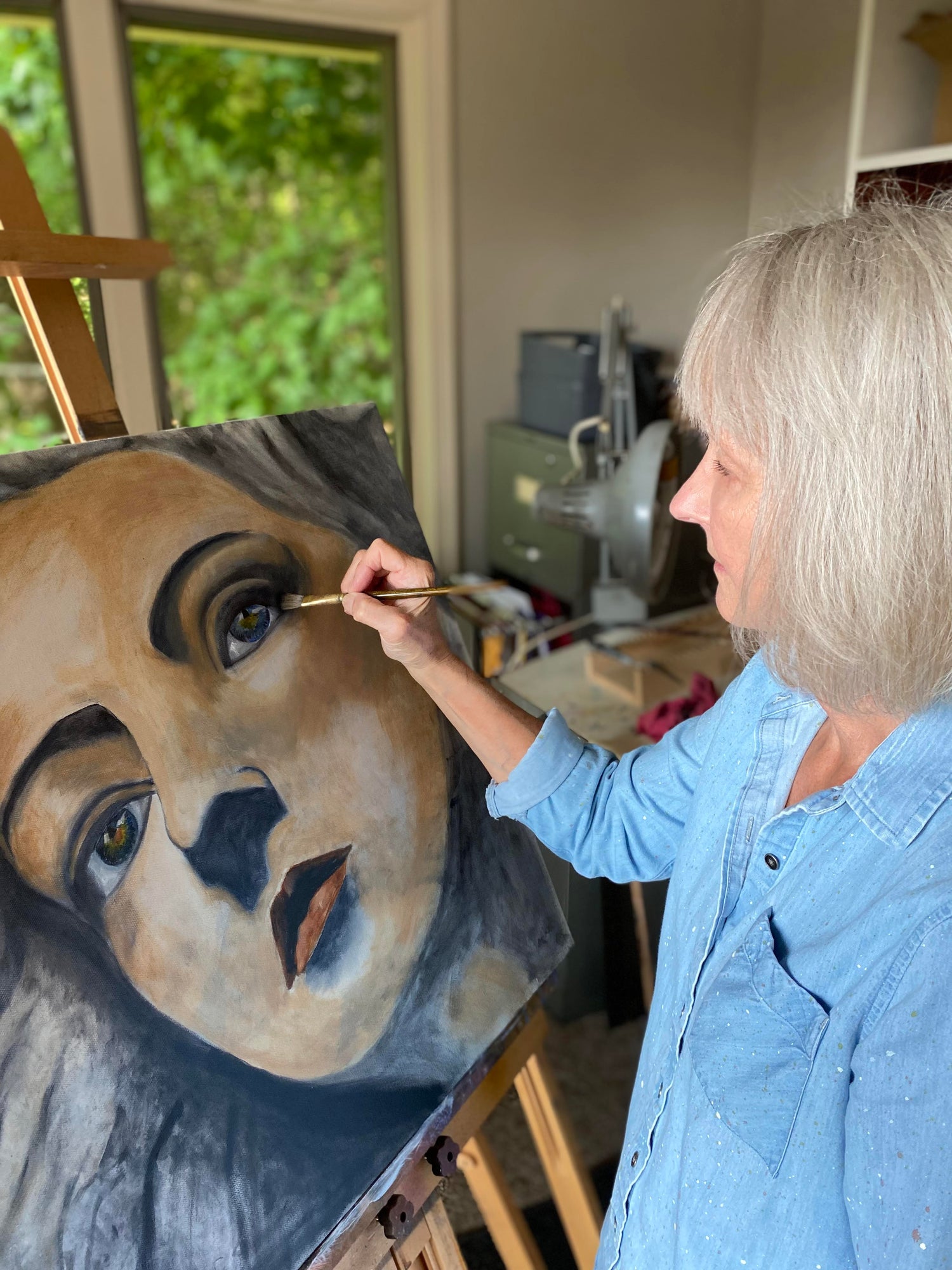 Waynesville, North Carolina based artist Carol Fetty painting a portrait painting of a woman's face at her easel in her art studio.